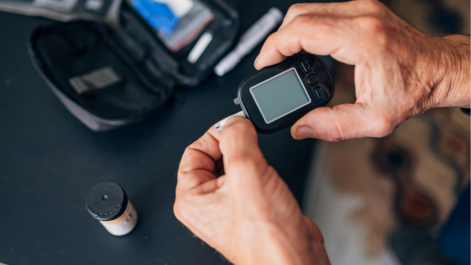  A man uses a blood glucose meter to check his glucose level.