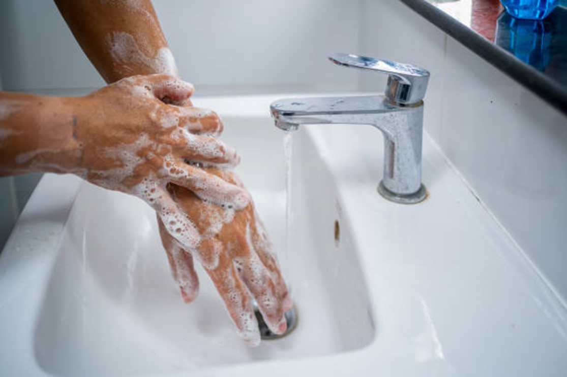 A person washing their hands at a sink.