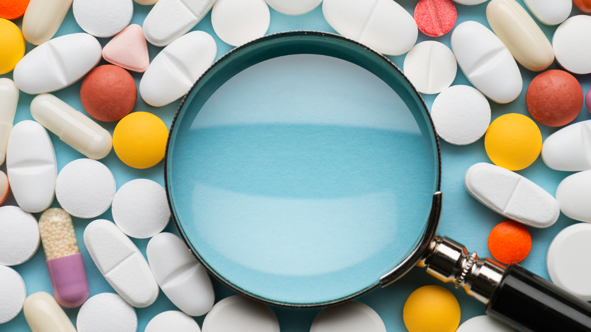 A decorative image of a magnifying glass looking at pills