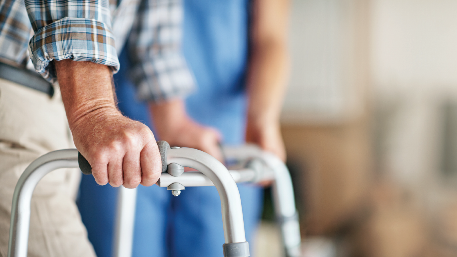 Close up view of a person's hands on a walker.