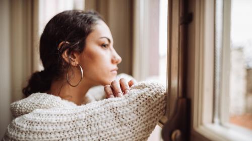 Woman looking through window, looking sad