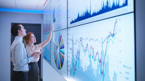 People collaborating near a white board with multiple charts