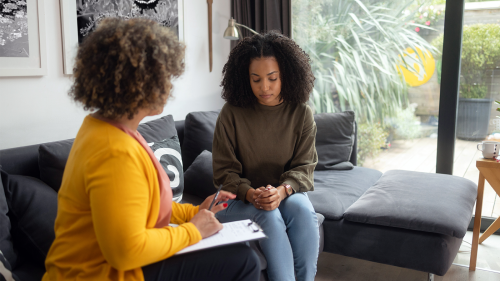 An African American teen girl talks to a female psychotherapist.