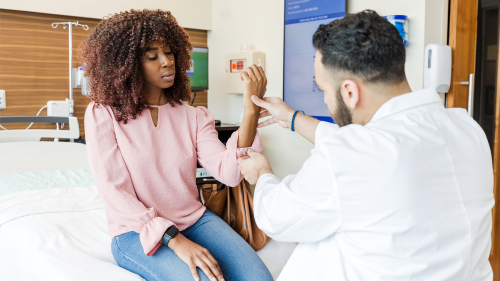 A doctor examines the arm of a female patient