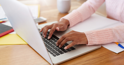 young African-American woman's hands typing on laptop keyboard