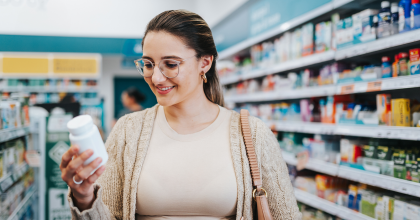 Young woman inside a pharmacy reviewing the presription label on a medication