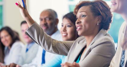 African American Businesswoman Raising Hand Asking Question In Business Conference