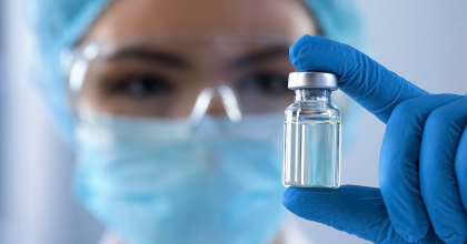 Scientist wearing protective glasses  holding vial with gloves