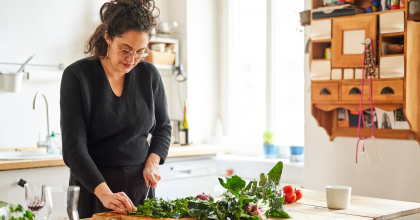 Woman chopping leafy green vegetables on her kitchen countertop