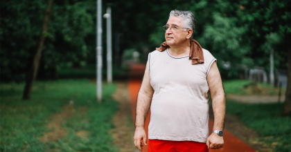 Older man exercising in the park looking off in the distance.