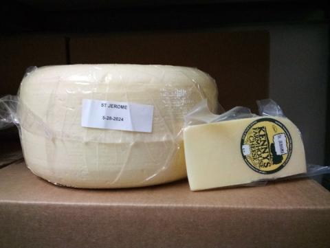 Kenny’s Farmhouse Cheese 15-pound wheel and 8-ounce St. Jerome cheese wedge in clear plastic packages