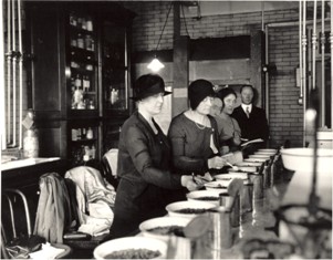 4 women standing behind a table looking at contents in bowls